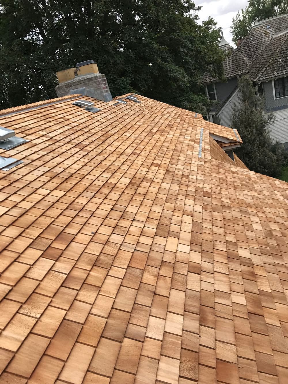 Close-up of a freshly installed cedar shingle roof with vibrant wood tones and skylights.