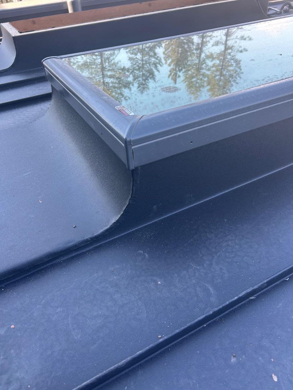 Low slope skylight flashing on a standing seam metal roof.